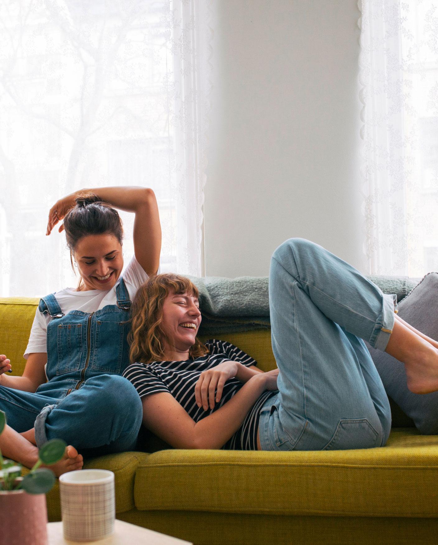 two women sitting on a couch laughing