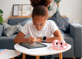 girl wearing smartwatch, using tablet with headphones on the table