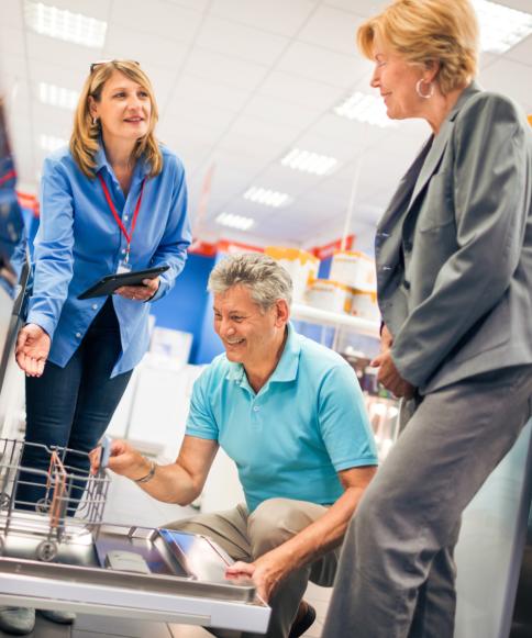 Sales associate showing dishwasher to man and woman
