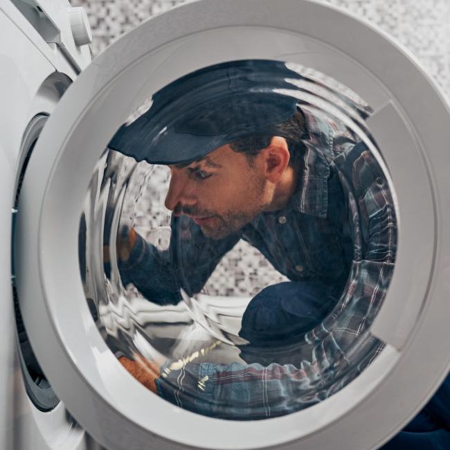 repair man looking in to dryer